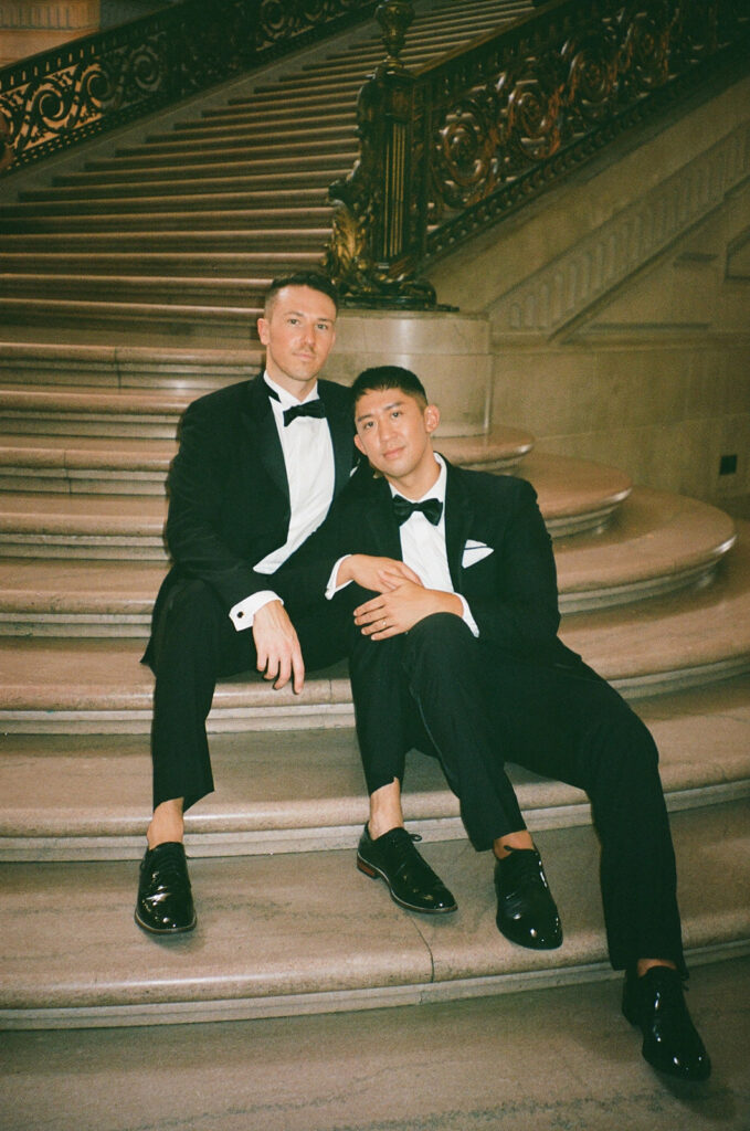 Film photo of grooms sitting on stairs of SF City Hall.