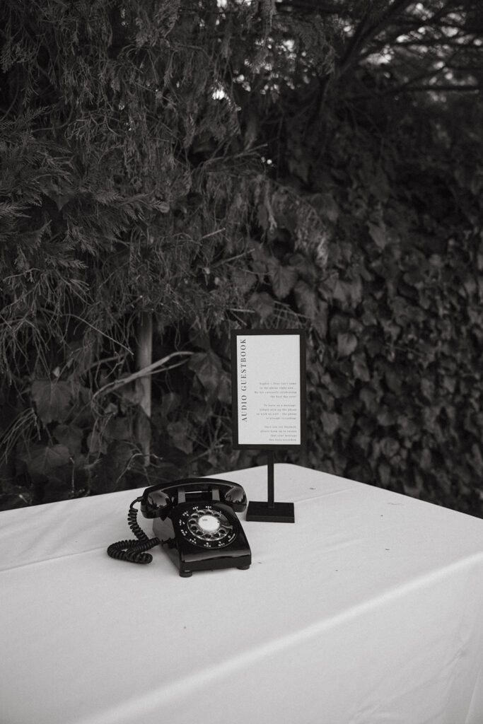 After the tone black rotary phone and sign on a table.