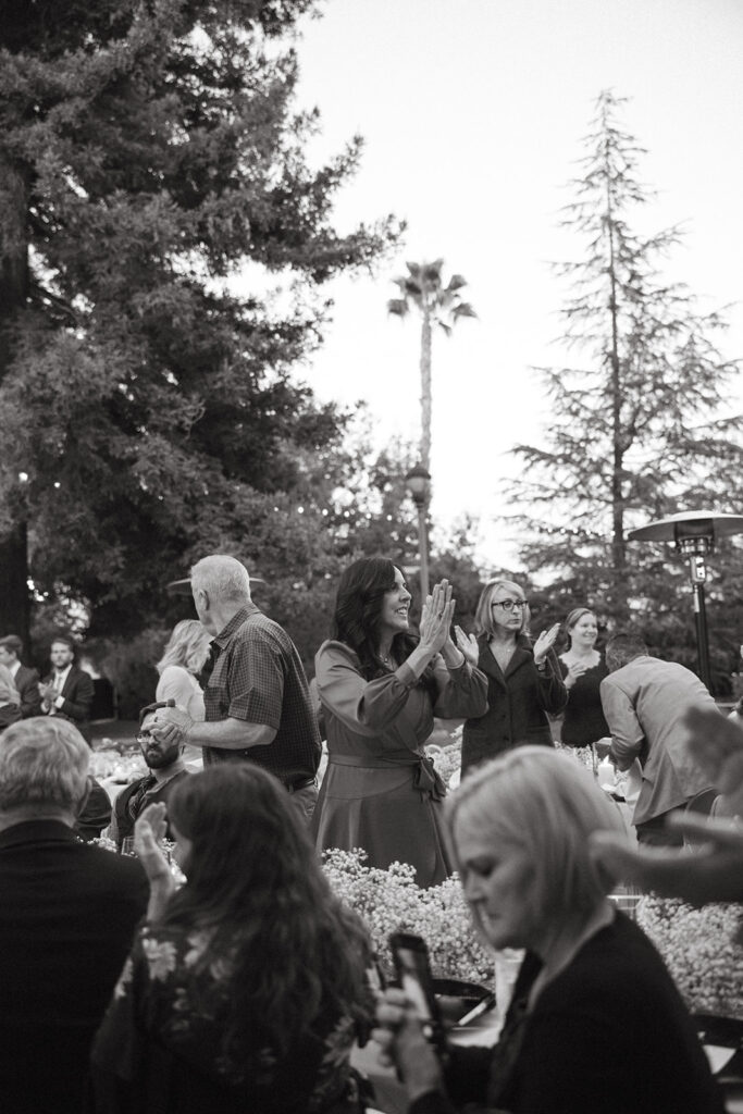 Wedding guests cheering and standing for grand entrance.