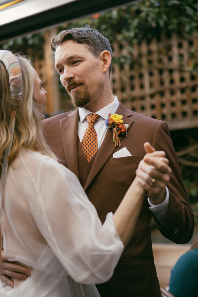 First dance photo. Groom has on rusty brown suit with an orange polka dot tie.