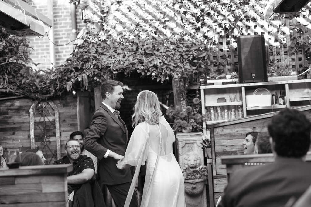 Bride and groom holding hands laughing and dancing.