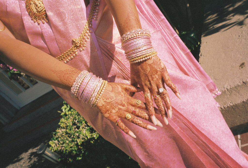 Film photo of the bridal henna and layers of pink and gold bangles and rings.