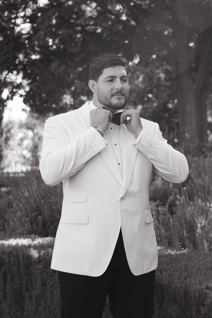 Groom pose fixing his black bow tie.