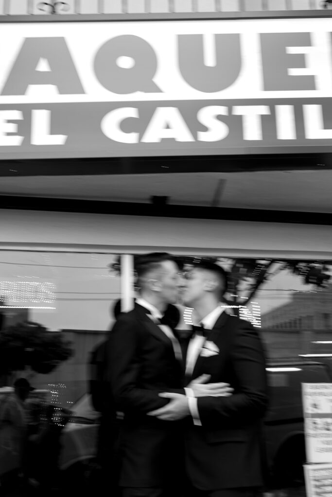 Blur of grooms kissing in front of a taqueria.