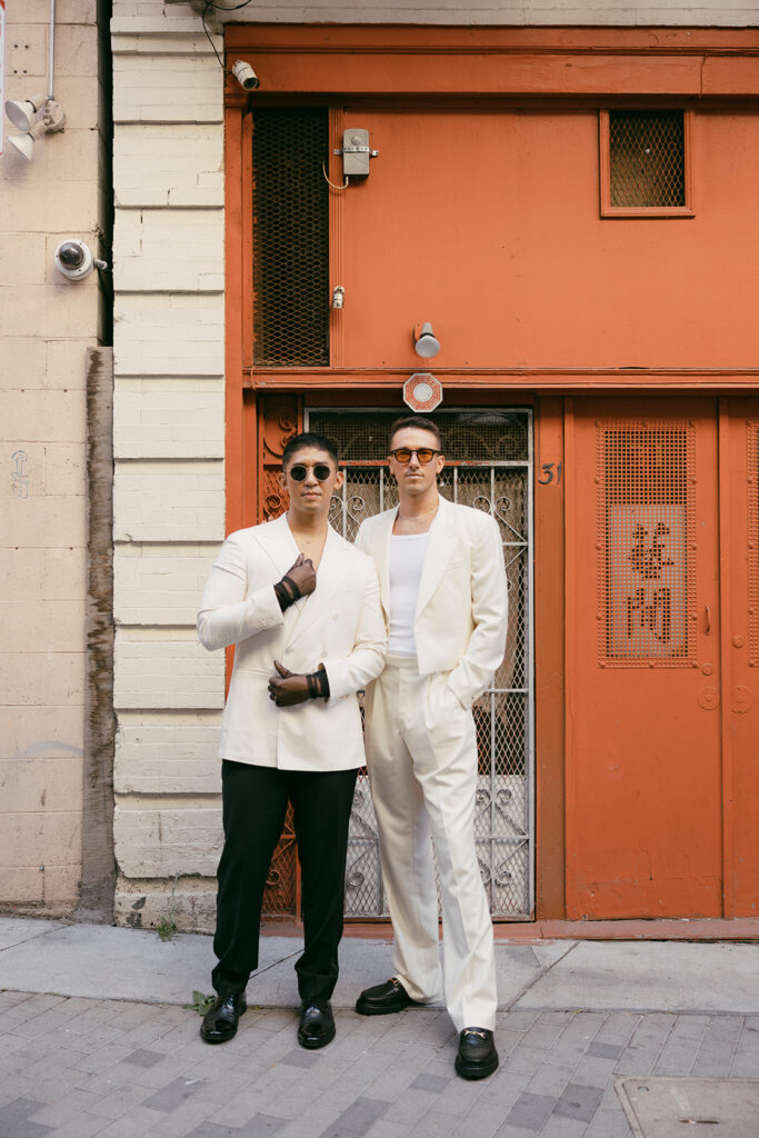 Two men posing in front red building in SF Chinatown.