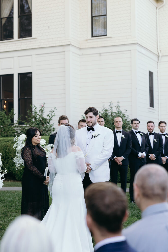 Groom holding back tears looking at bride at ceremony.