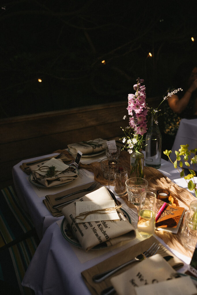 Restaurant wedding tablescape table setting with rosemary garnish tied in with jute string and simple florals as centerpieces.