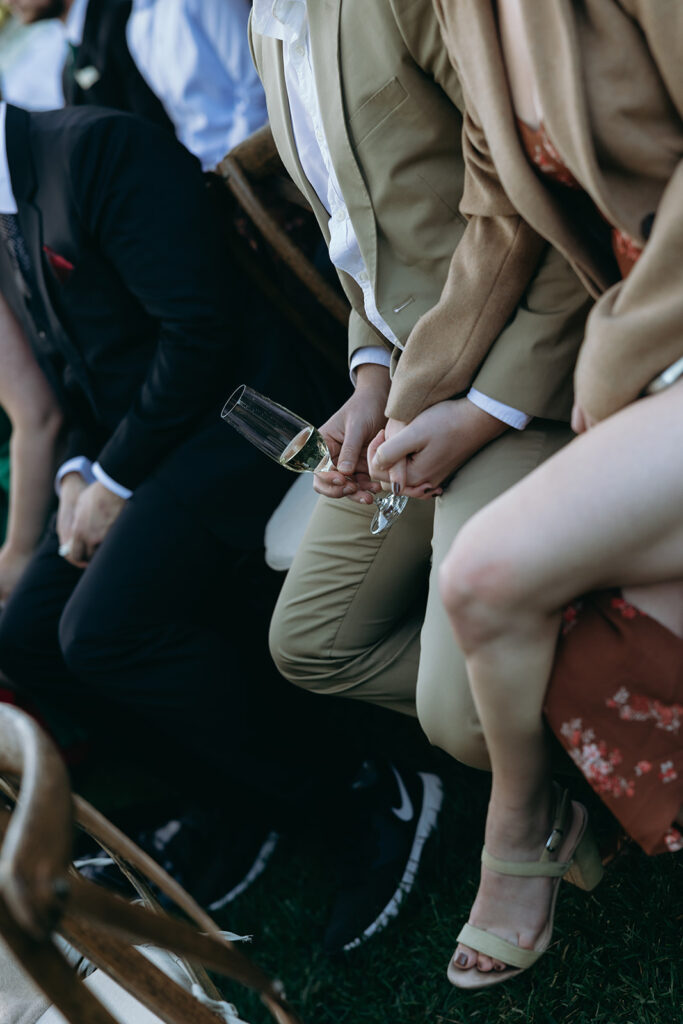 Wedding guest during ceremony holding a glass of champagne.