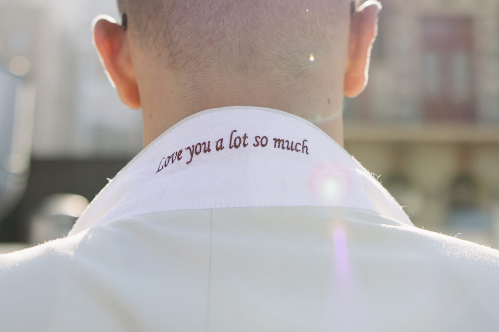 White collar with embroidered text underneath that says "Love you a lot so much" in red thread.