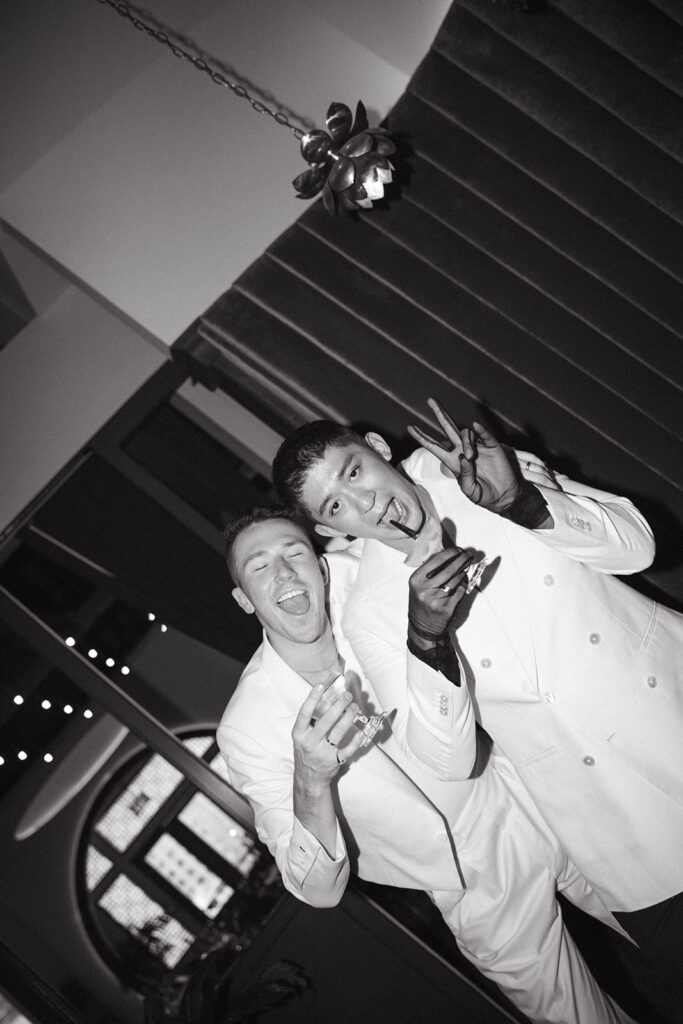 Grooms holding a cocktail and posing silly for the camera.