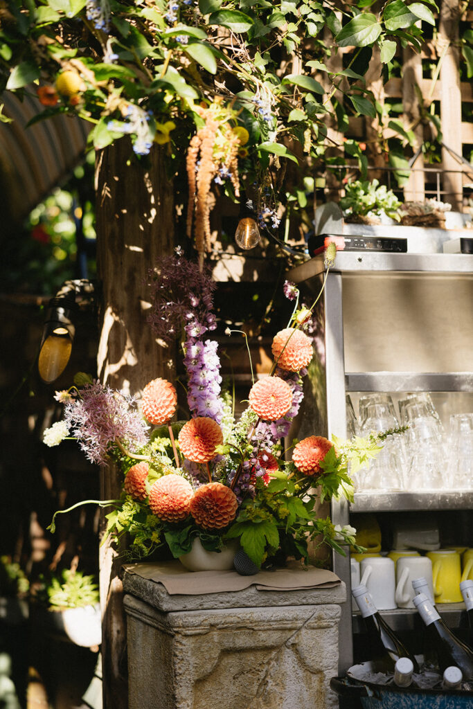 Large purple and orange dahlia bar floral arrangement outside on a pillar.
