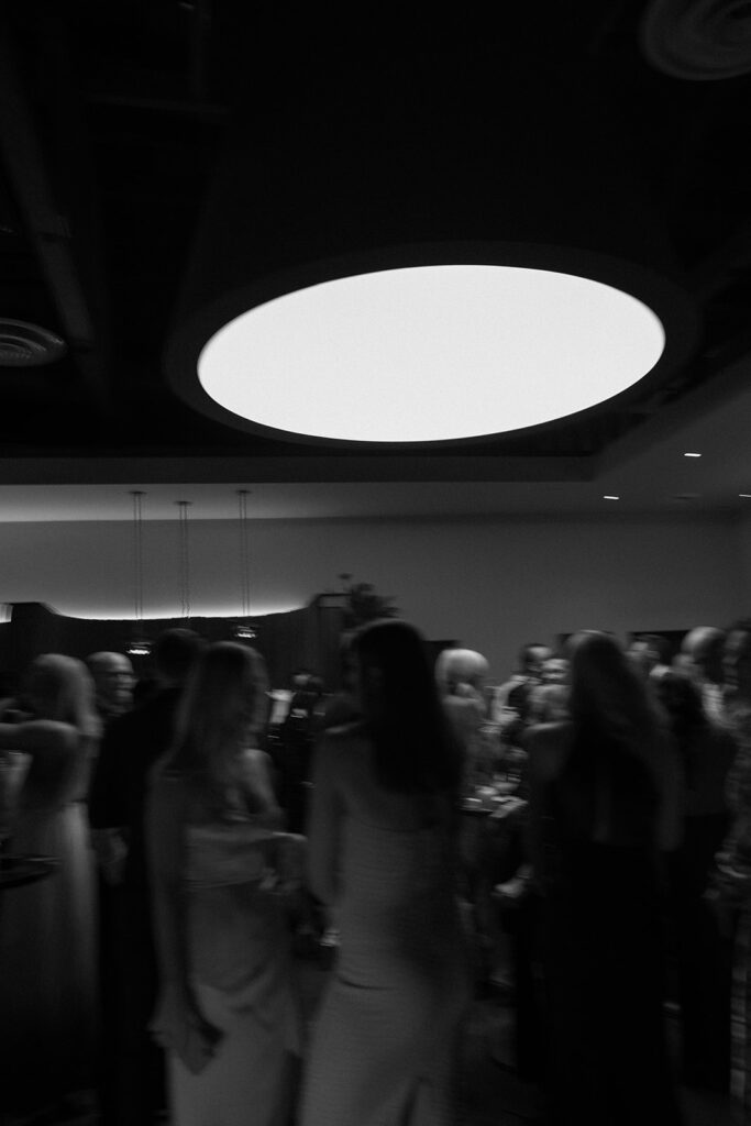 Moody dancefloor photo in black and white with large round overhead lighting.