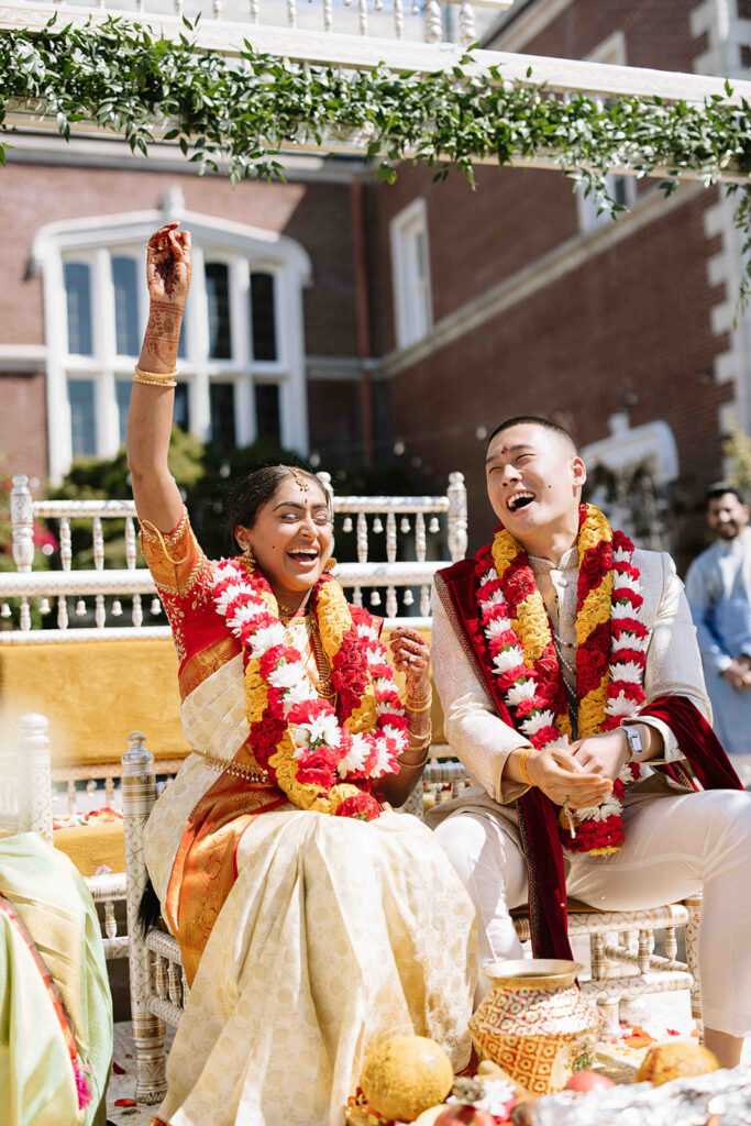 Bride and groom during traditional Indian wedding ceremony cheering and laughing together.