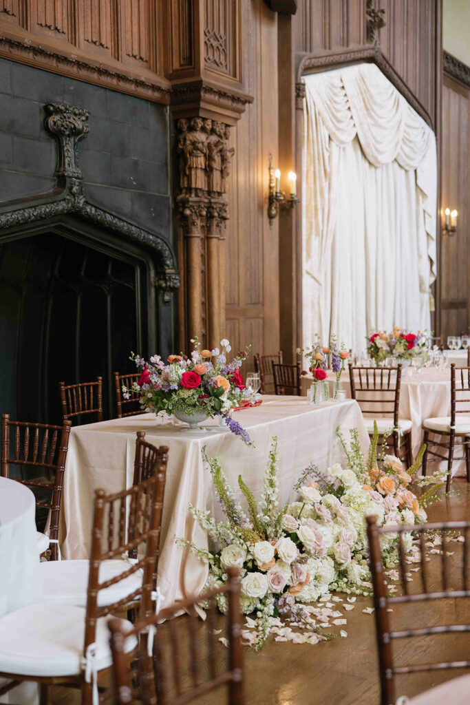 Luxury indoor wedding reception in front of a black fireplace with wood walls and draping.