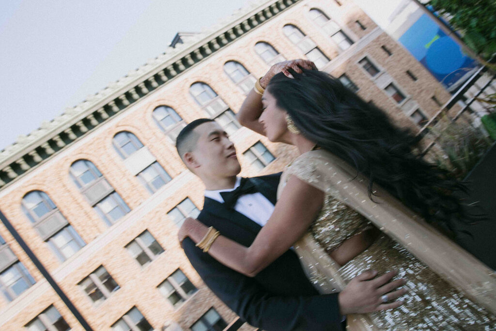Motion blue photo of bride fixing her hair while holding onto the groom and he stares lovingly at her.