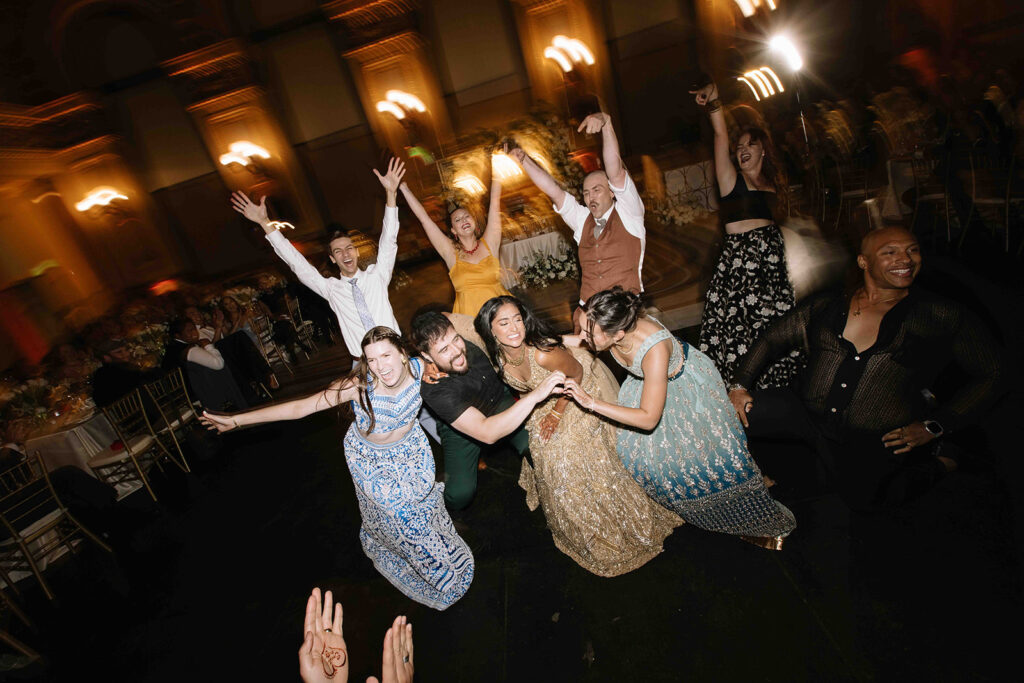 Wedding guests dancing and posing with the bride on the dancefloor.