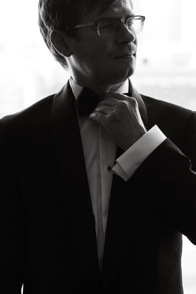 Groom fixing his tie while looking off in the distance