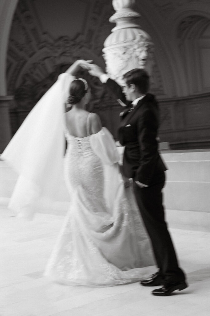 Groom twirling his bride while holding her hand in a motion blue photo
