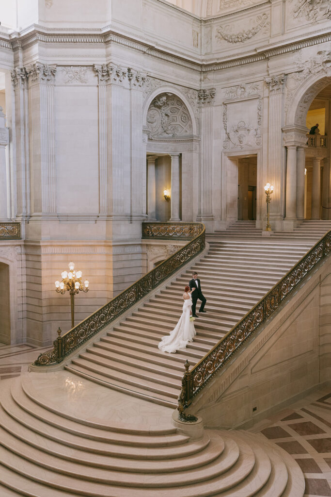 Groom leading bride up the grand staircase at SF city hall