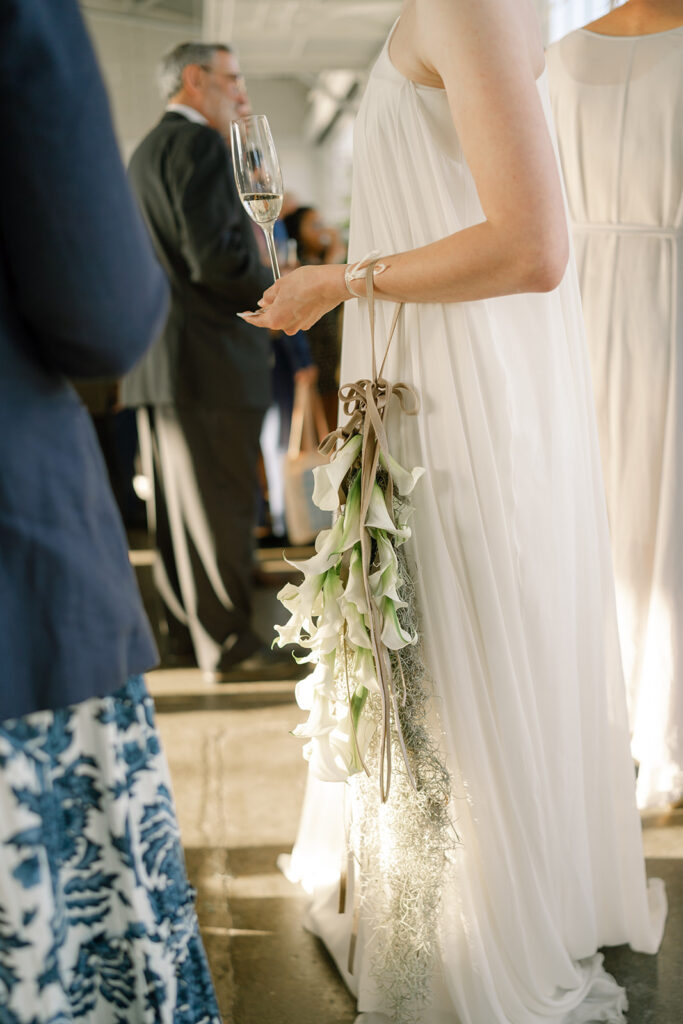 wedding bouquet on brides wrist while she holds a glass of champagne