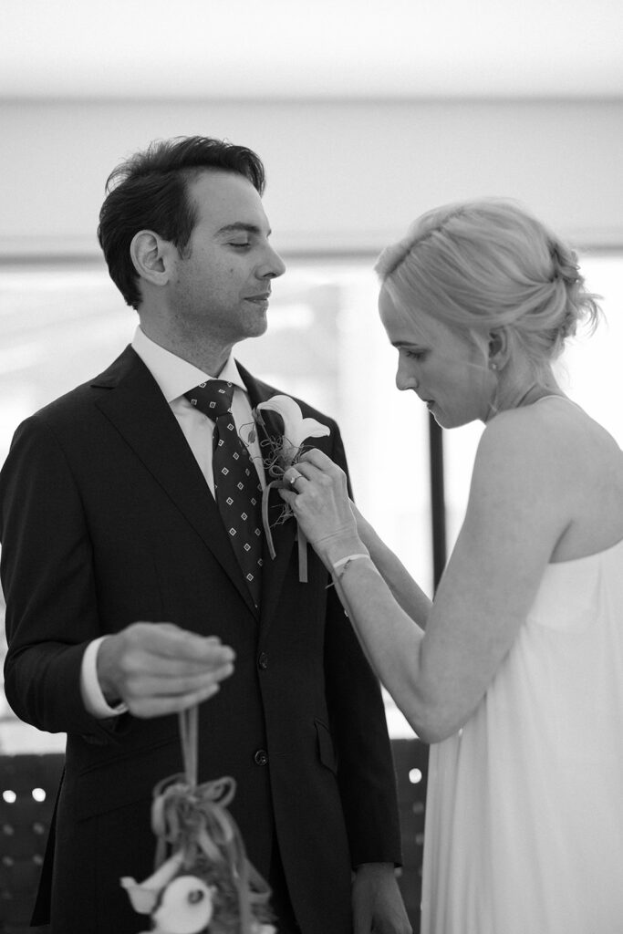 Bride pinning lily boutonniere on groom