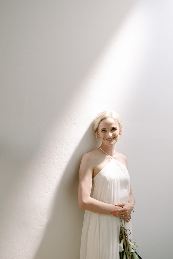 Bride against a wall with a beautiful strip of golden lighting above her.