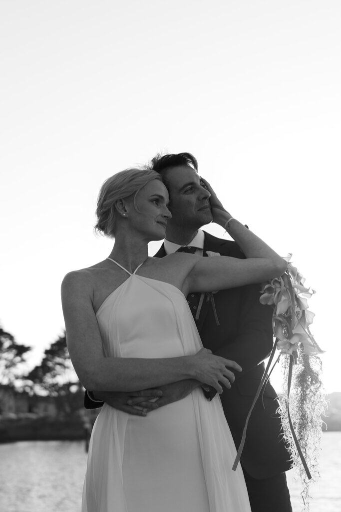 Bride in front of groom holding his head as he has his arms wrapped around her