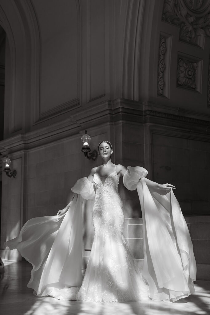 Bride holding her arms out letting her sleeves fabric flow around her mermaid wedding gown