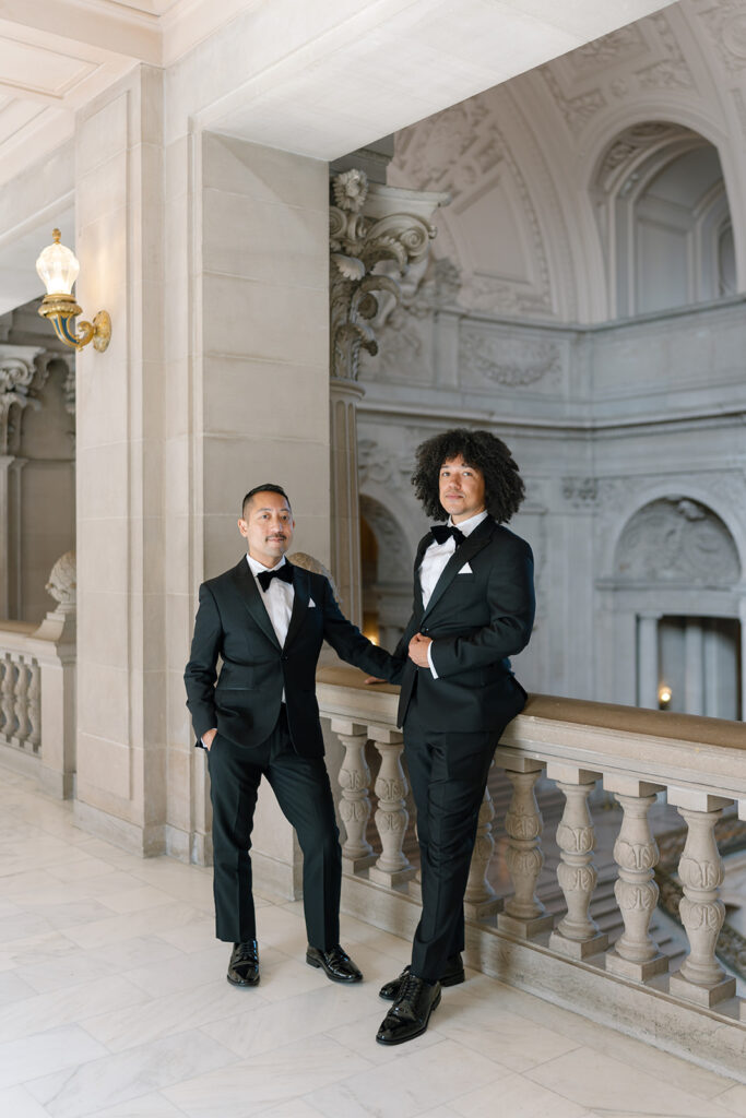 Grooms standing staggered against a balcony
