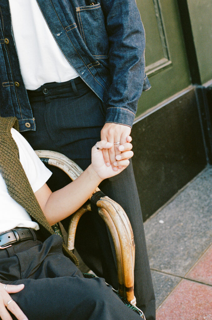Editorial couples photography, gay couple holding hands while sitting at a cafe