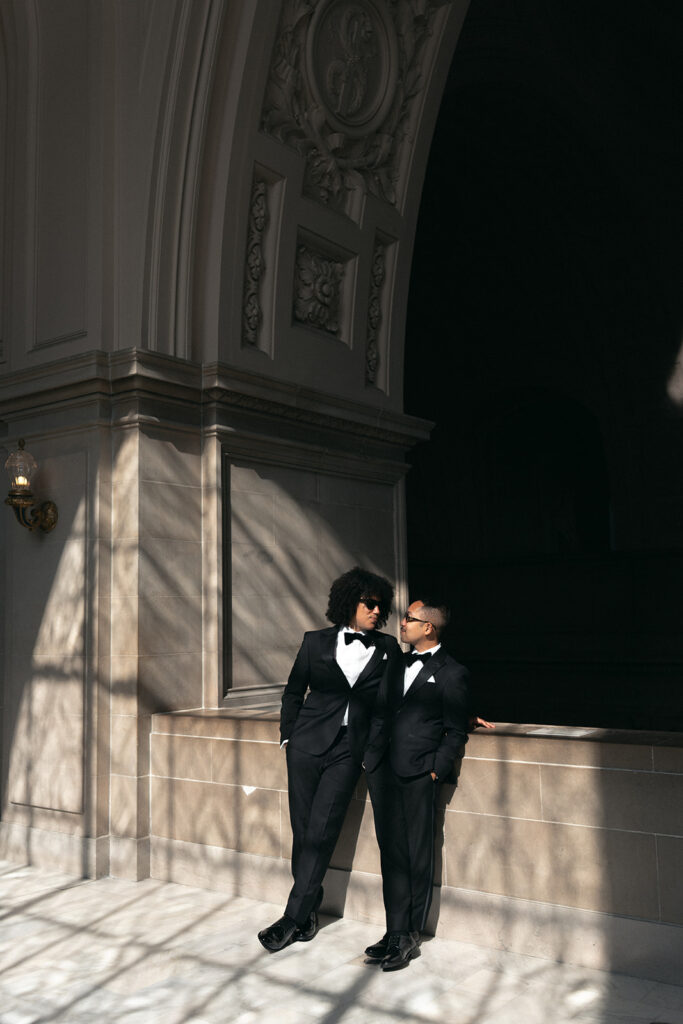 Grooms standing in window shadow light looking at each other lovingly